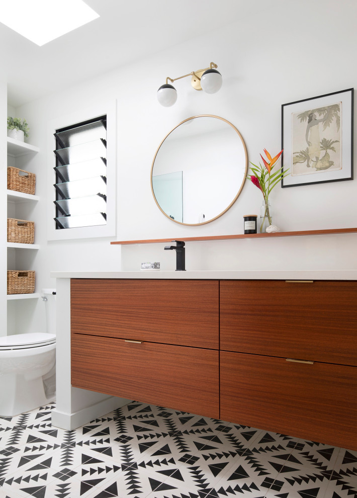 This is an example of a small contemporary master bathroom in Hawaii with flat-panel cabinets, medium wood cabinets, an alcove shower, a two-piece toilet, white tile, ceramic tile, white walls, cement tiles, an undermount sink, engineered quartz benchtops, black floor, a hinged shower door, white benchtops, a niche, a single vanity and a floating vanity.