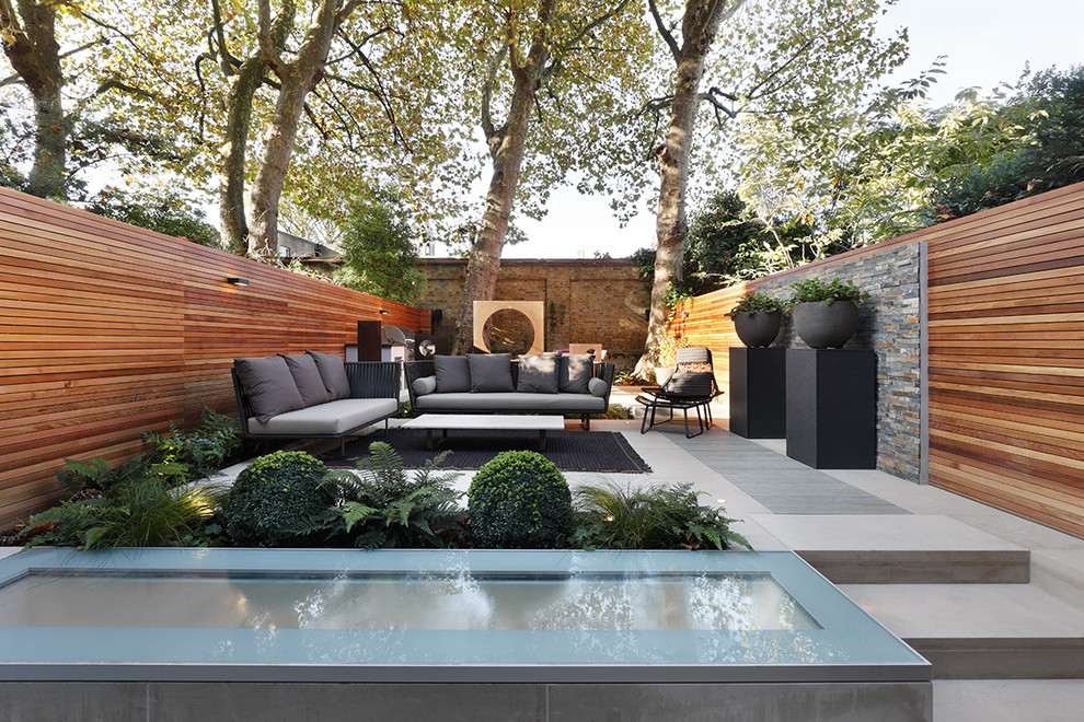 This is an example of a mid-sized contemporary backyard patio in London with a container garden and natural stone pavers.