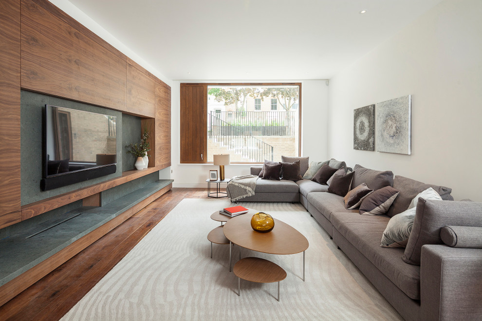 Photo of an expansive contemporary family room in Hertfordshire with white walls, dark hardwood floors, a wall-mounted tv, brown floor and wood walls.