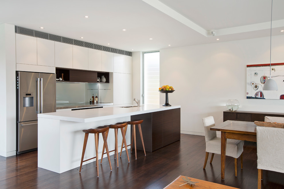 This is an example of a contemporary kitchen in Sydney with a double-bowl sink, white cabinets, stainless steel appliances, dark hardwood floors, with island and flat-panel cabinets.