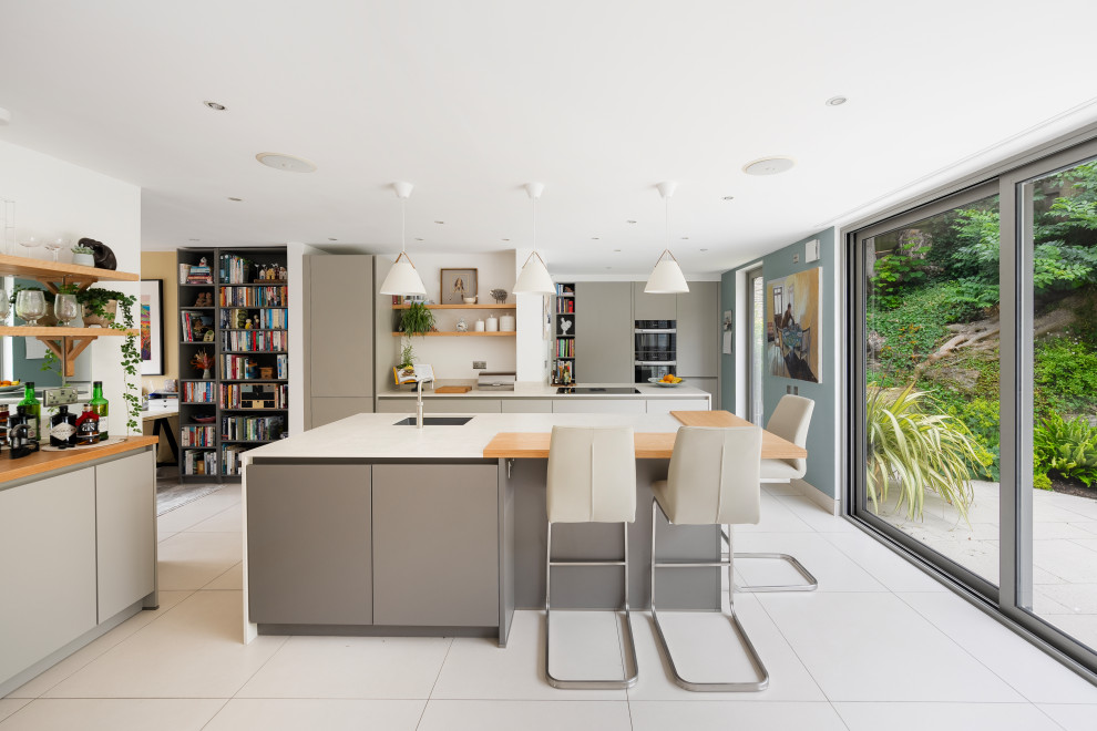 Photo of a contemporary l-shaped kitchen in Devon with an undermount sink, flat-panel cabinets, grey cabinets, with island, white floor and white benchtop.