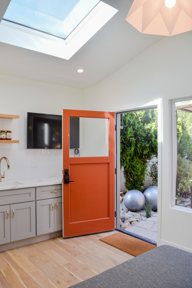 Design ideas for a small traditional front door in Los Angeles with white walls, laminate floors, a single front door, an orange front door, brown floor and vaulted.