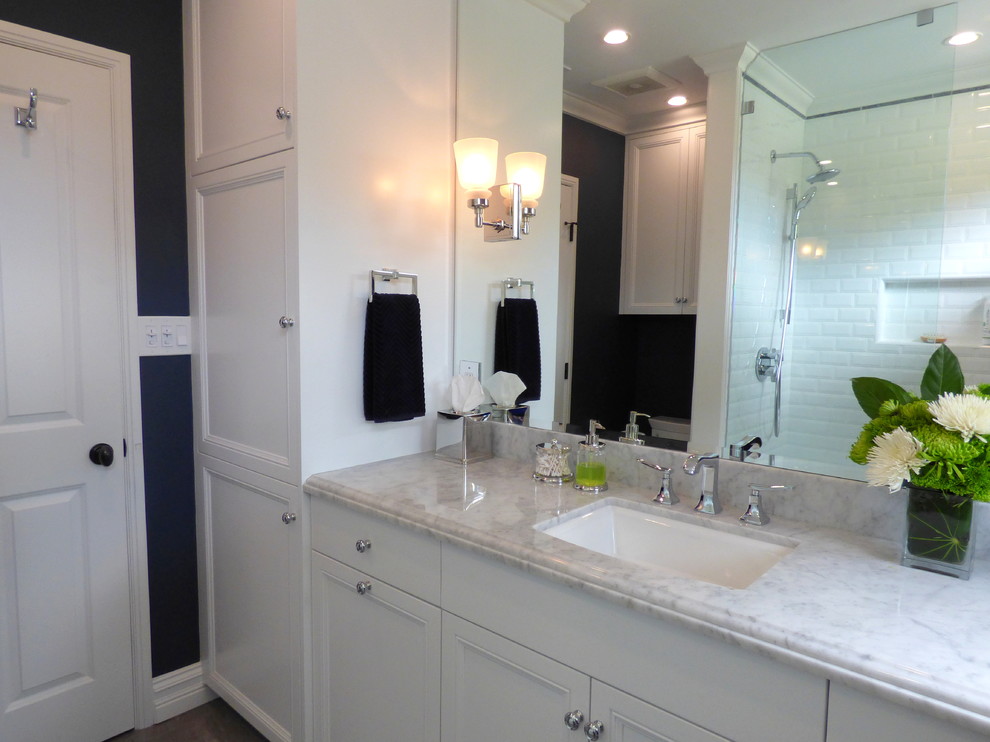 This is an example of a small traditional 3/4 bathroom in Los Angeles with an undermount sink, flat-panel cabinets, white cabinets, marble benchtops, an alcove shower, a one-piece toilet, white tile, subway tile, blue walls and porcelain floors.