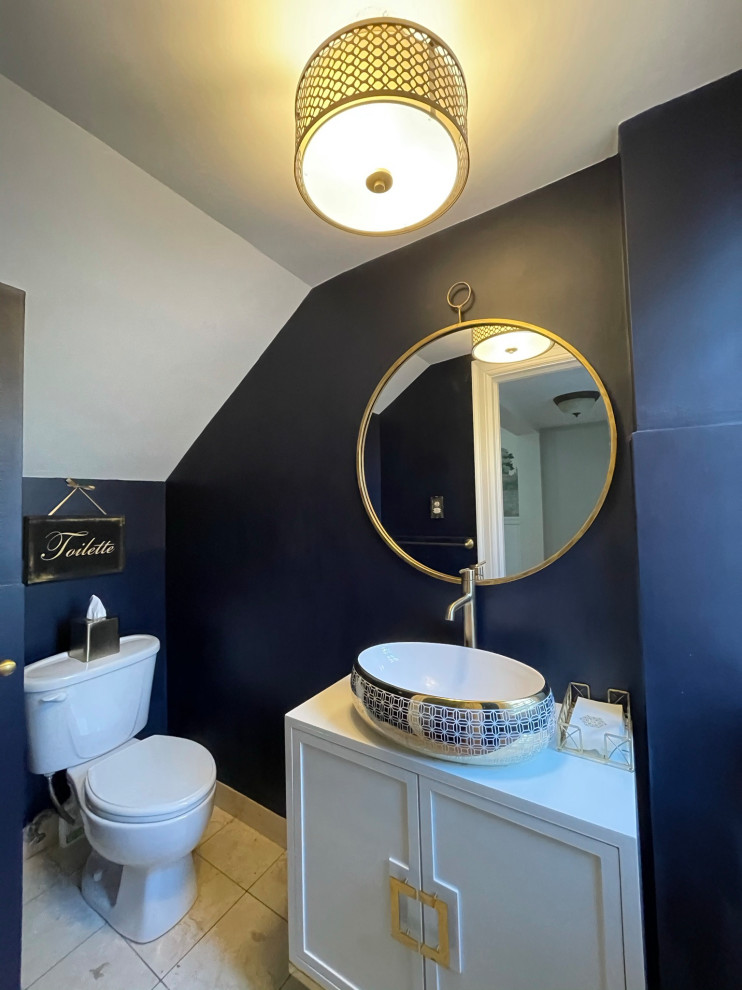 Photo of a small midcentury powder room in New York with shaker cabinets, white cabinets, a two-piece toilet, blue walls, marble floors, a vessel sink, beige floor and a freestanding vanity.
