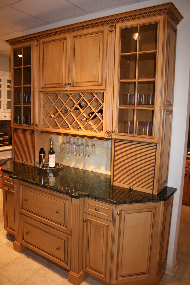 Large traditional l-shaped home bar in New York with an undermount sink, raised-panel cabinets, dark wood cabinets, granite benchtops, beige splashback, stone tile splashback and ceramic floors.