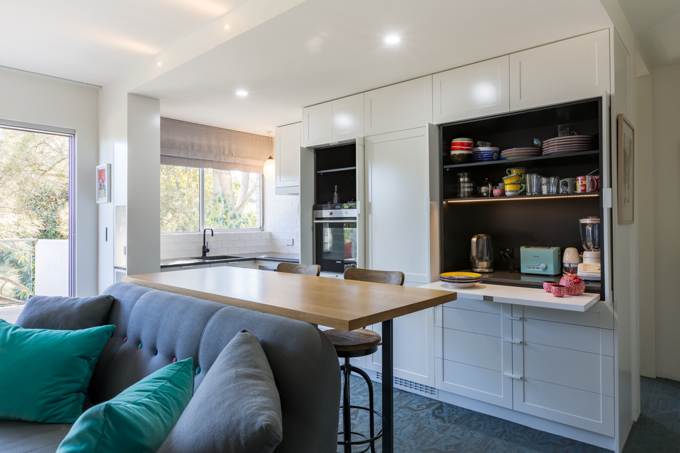 Design ideas for a small transitional l-shaped open plan kitchen in Sydney with an undermount sink, recessed-panel cabinets, white cabinets, quartz benchtops, white splashback, ceramic splashback, stainless steel appliances, linoleum floors, no island and green floor.