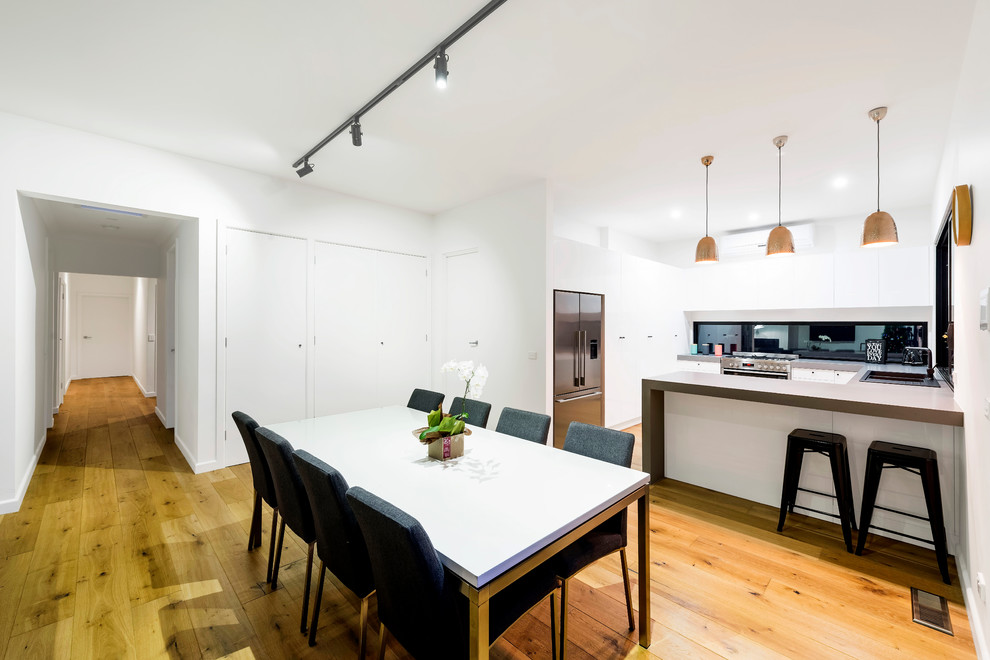 Mid-sized modern kitchen/dining combo in Melbourne with white walls, medium hardwood floors and no fireplace.