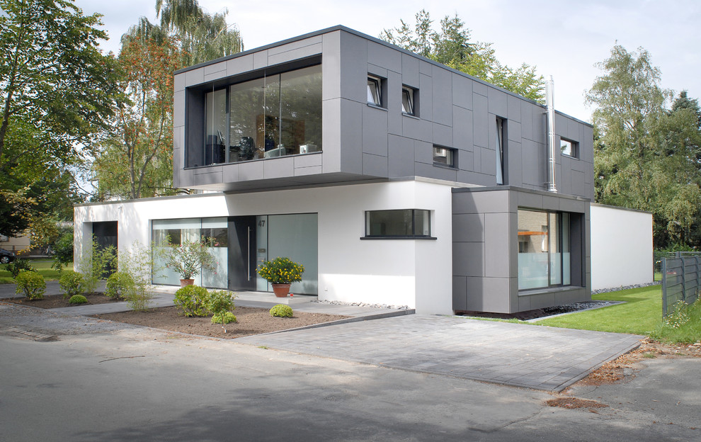 Mid-sized modern split-level stucco white house exterior in Other with a flat roof.