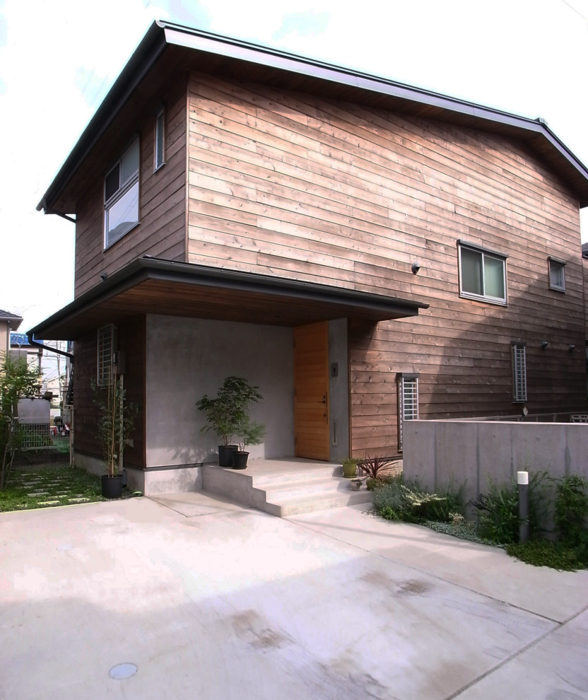 Réalisation d'une petite façade de maison marron chalet en bois et bardeaux à un étage avec un toit à deux pans, un toit en métal et un toit noir.