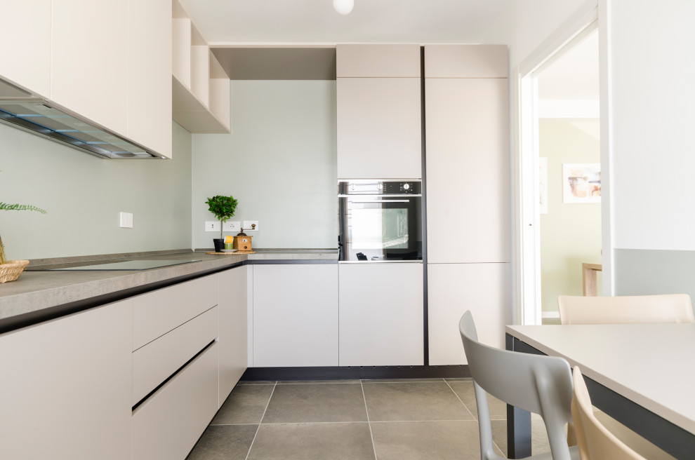 Design ideas for an expansive contemporary l-shaped separate kitchen in Milan with a double-bowl sink, flat-panel cabinets, beige cabinets, solid surface benchtops, green splashback, brick splashback, panelled appliances, porcelain floors, no island, brown floor and multi-coloured benchtop.