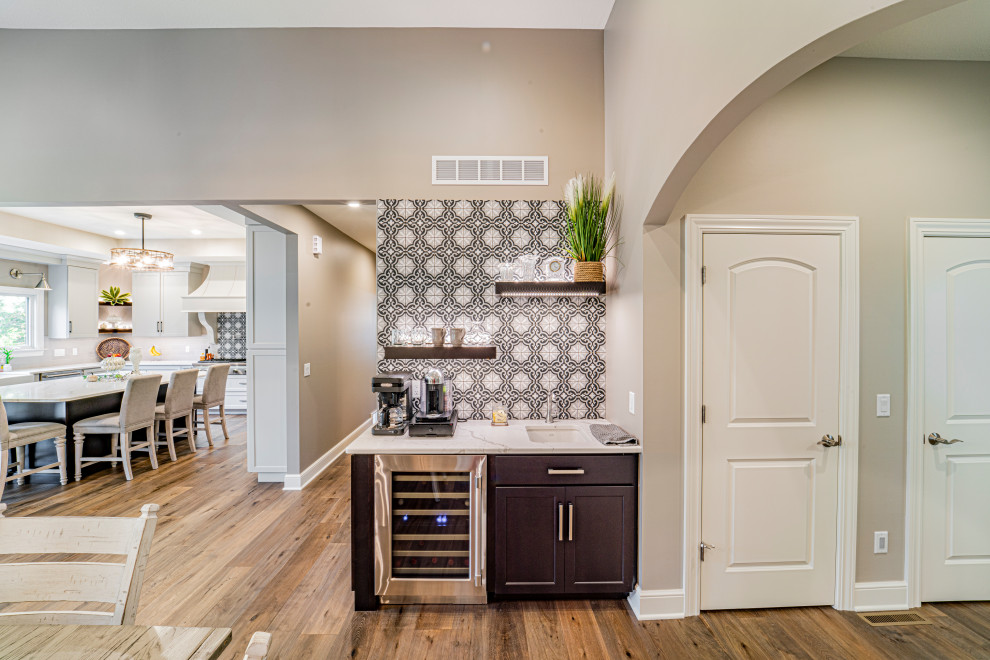 Mid-sized transitional medium tone wood floor and beige floor wet bar photo in Other with an undermount sink, shaker cabinets, dark wood cabinets, quartzite countertops, multicolored backsplash, porcelain backsplash and white countertops
