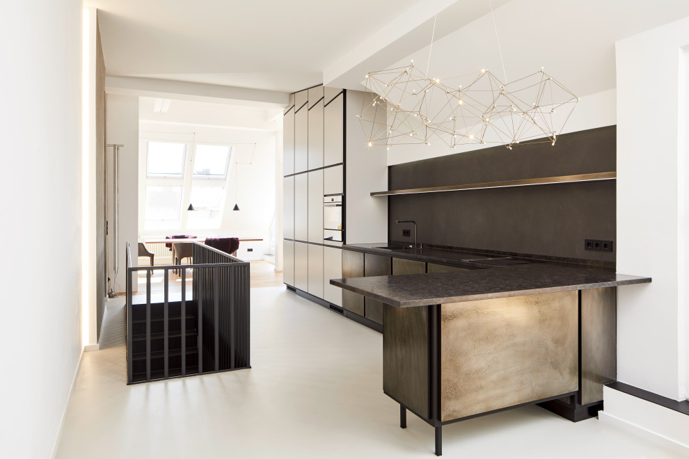 Offene, Große Moderne grifflose Küche in L-Form mit Unterbauwaschbecken, flächenbündigen Schrankfronten, braunen Schränken, Granit-Arbeitsplatte, Küchenrückwand in Grau, Betonboden, Halbinsel, beigem Boden und grauer Arbeitsplatte in Berlin