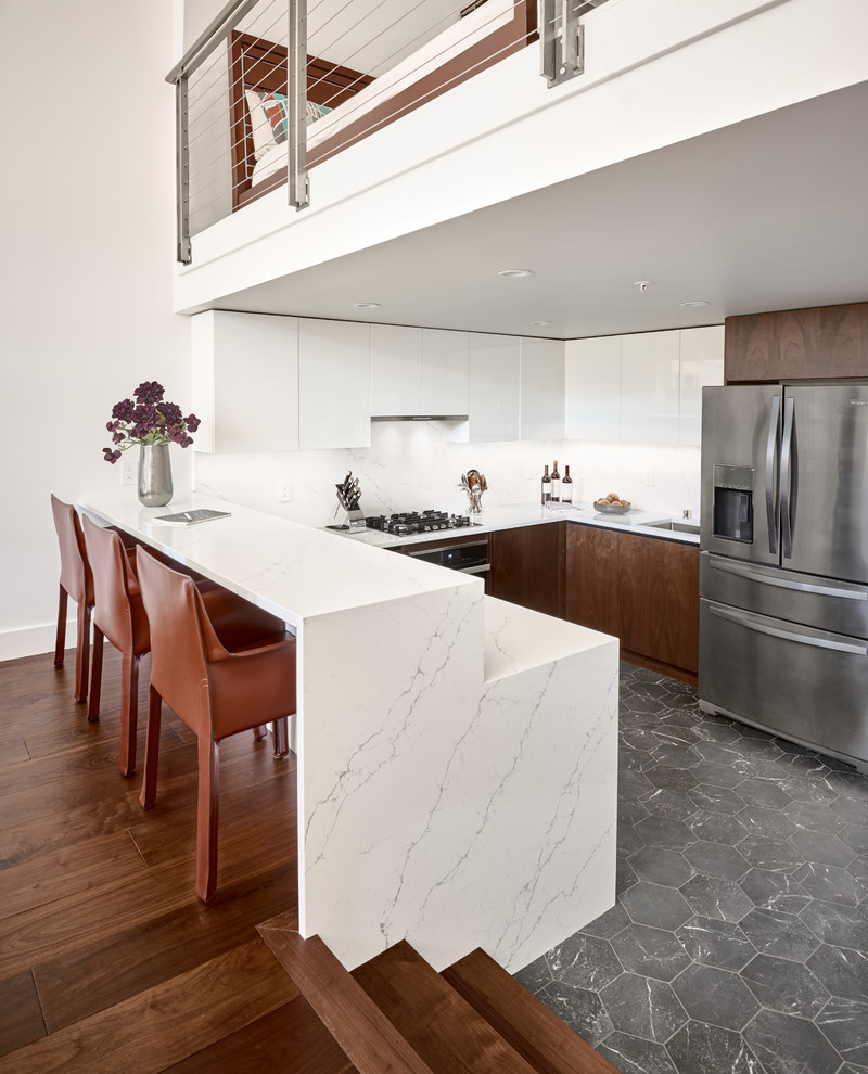 Inspiration for a contemporary u-shaped kitchen in San Francisco with an undermount sink, flat-panel cabinets, white cabinets, white splashback, stainless steel appliances, a peninsula, grey floor and white benchtop.