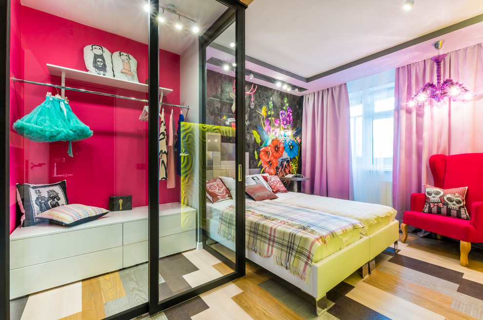 This is an example of a contemporary kids' bedroom for girls in Other with pink walls, multi-coloured floor and medium hardwood floors.