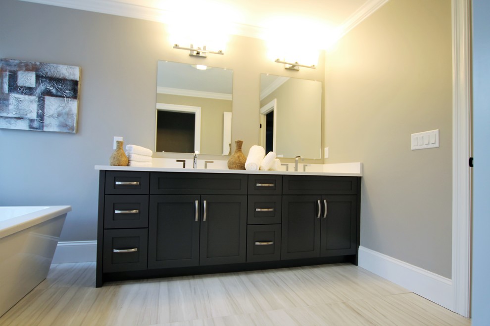 Inspiration for a large transitional master porcelain tile and gray floor freestanding bathtub remodel in Boston with shaker cabinets, a two-piece toilet, beige walls, an undermount sink, granite countertops and black cabinets