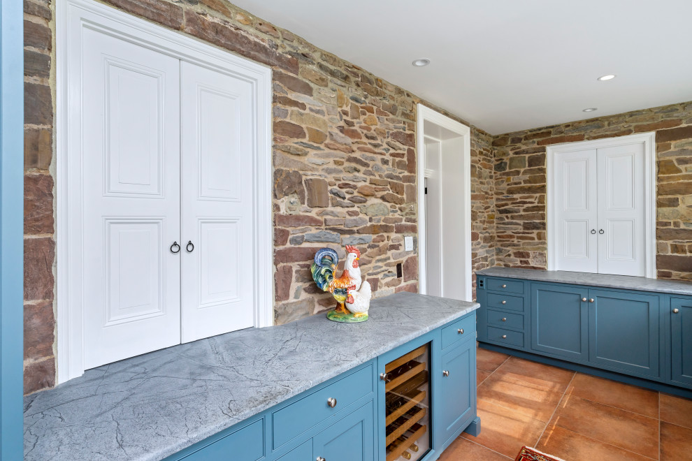 This is an example of a large rural l-shaped enclosed kitchen in Philadelphia with a belfast sink, beaded cabinets, blue cabinets, soapstone worktops, blue splashback, ceramic splashback, integrated appliances, porcelain flooring, an island, orange floors, black worktops and a drop ceiling.
