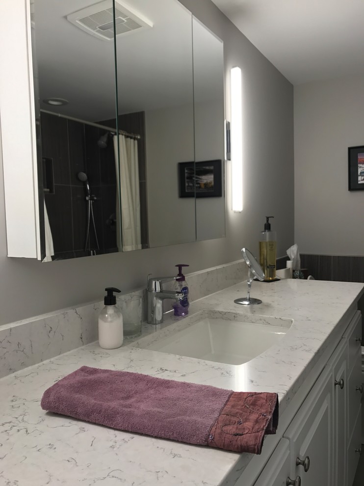 Mid-sized transitional 3/4 black tile and porcelain tile laminate floor and black floor alcove shower photo with raised-panel cabinets, white cabinets, a two-piece toilet, gray walls, an undermount sink, marble countertops and white countertops