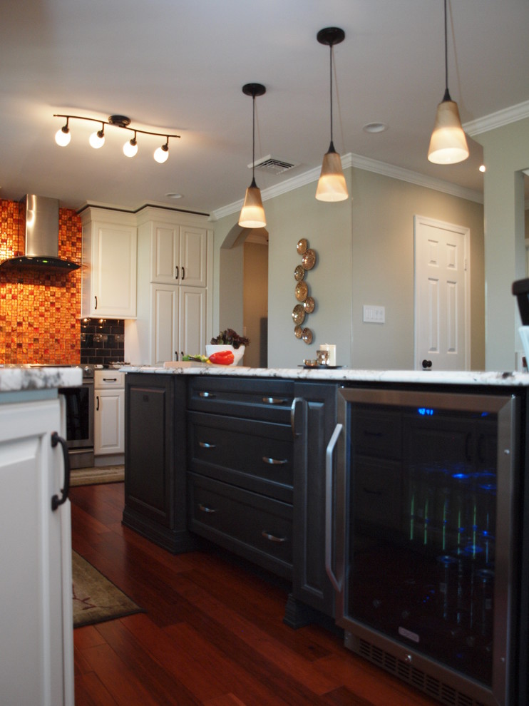 Large transitional medium tone wood floor eat-in kitchen photo in Philadelphia with an undermount sink, raised-panel cabinets, white cabinets, granite countertops, black backsplash, ceramic backsplash, stainless steel appliances and an island