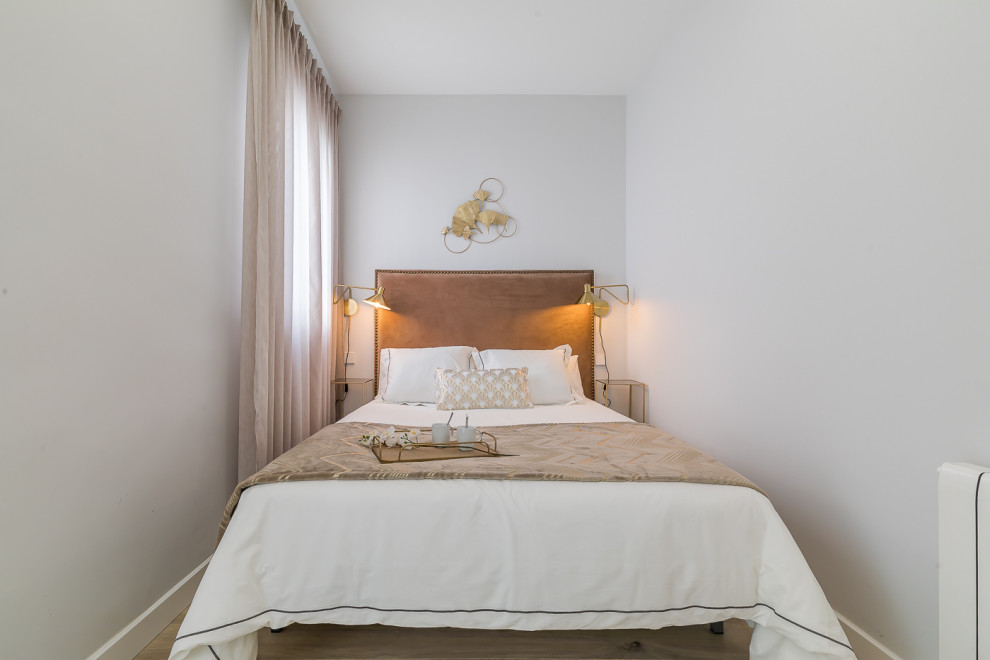 Diseño de dormitorio principal y beige y blanco tradicional renovado pequeño con paredes blancas, suelo de madera en tonos medios y suelo marrón
