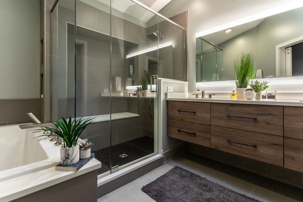 Mid-sized modern bathroom in Chicago with flat-panel cabinets, medium wood cabinets, a drop-in tub, gray tile, grey walls, a drop-in sink, granite benchtops, grey floor, a hinged shower door, white benchtops, a shower seat, a double vanity, a floating vanity, porcelain tile and porcelain floors.