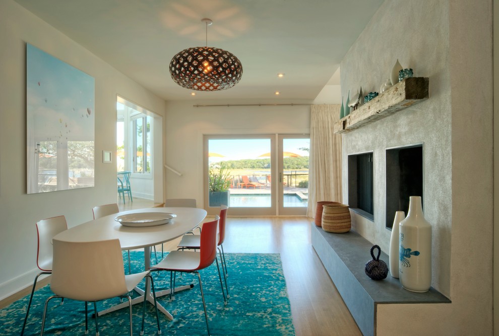 This is an example of a beach style dining room in New York with beige walls, medium hardwood floors and a standard fireplace.
