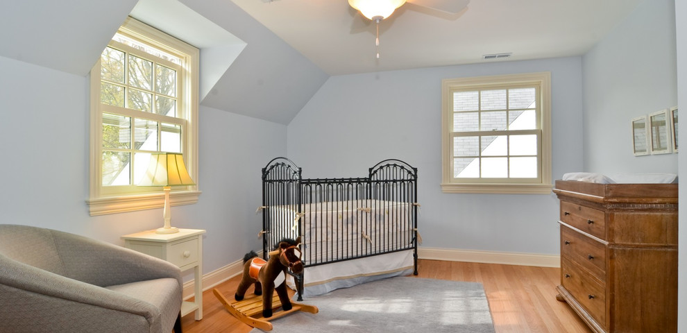 This is an example of a mid-sized traditional gender-neutral kids' bedroom in Chicago with blue walls and light hardwood floors.