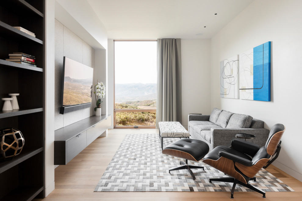 Modelo de sala de estar abierta y blanca minimalista con paredes blancas, suelo de madera clara y televisor colgado en la pared