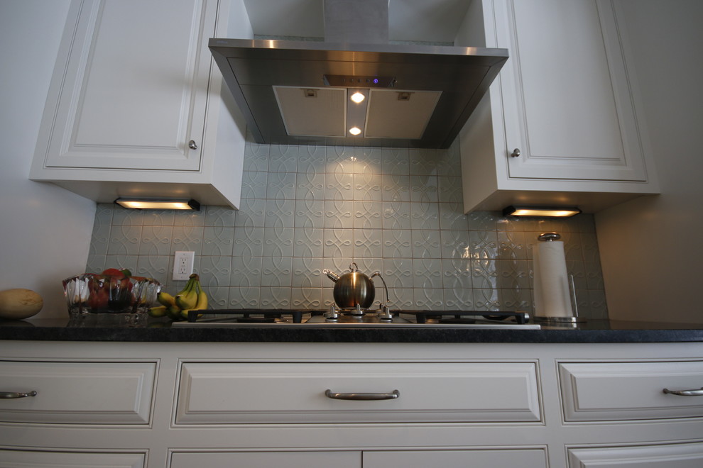 Large transitional medium tone wood floor enclosed kitchen photo in Cleveland with an undermount sink, beaded inset cabinets, white cabinets, quartzite countertops, blue backsplash, ceramic backsplash, stainless steel appliances, blue walls and an island