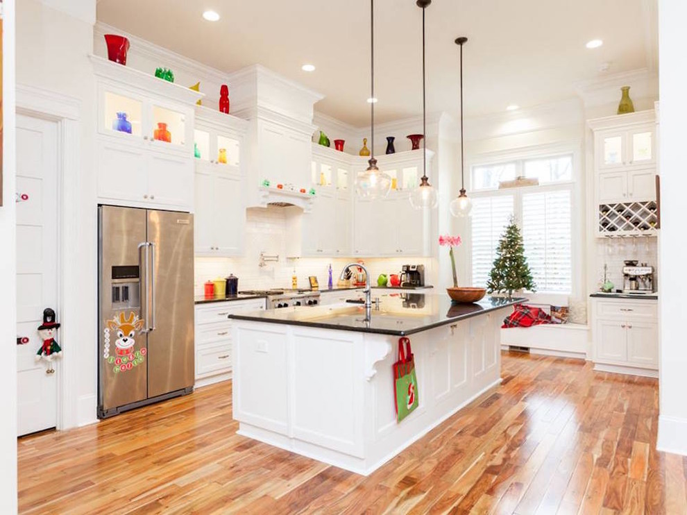 Inspiration for a large transitional u-shaped medium tone wood floor and multicolored floor open concept kitchen remodel with a farmhouse sink, recessed-panel cabinets, white cabinets, quartz countertops, white backsplash, subway tile backsplash, stainless steel appliances, an island and black countertops