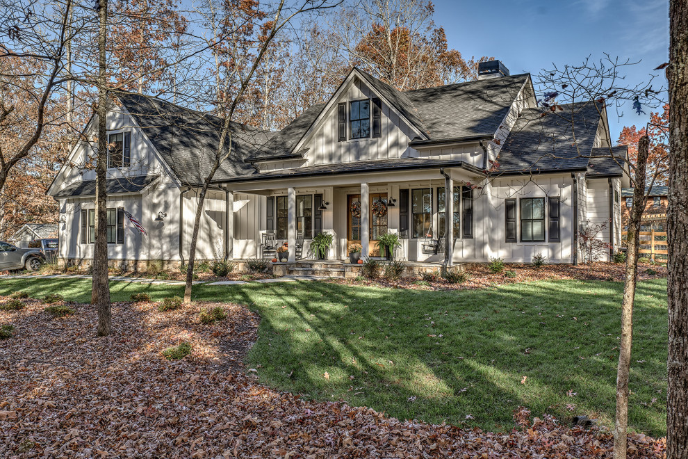 This is an example of a large country two-storey white house exterior in Atlanta with concrete fiberboard siding, a gable roof, a shingle roof, a black roof and board and batten siding.