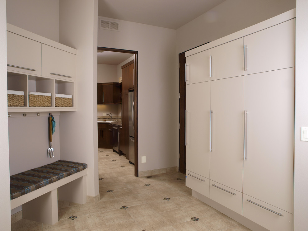 Inspiration for a mid-sized contemporary l-shaped utility room in Denver with a drop-in sink, flat-panel cabinets, dark wood cabinets, white walls, porcelain floors and beige floor.