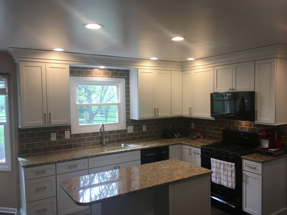 Example of a mid-sized transitional u-shaped dark wood floor and gray floor eat-in kitchen design with an undermount sink, shaker cabinets, white cabinets, granite countertops, gray backsplash, ceramic backsplash, black appliances, an island and beige countertops