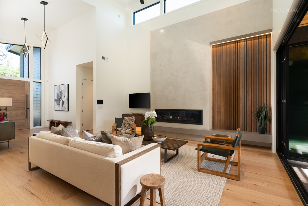 Large modern open concept living room in Portland with white walls, light hardwood floors, a ribbon fireplace, a plaster fireplace surround, a wall-mounted tv, brown floor and wallpaper.