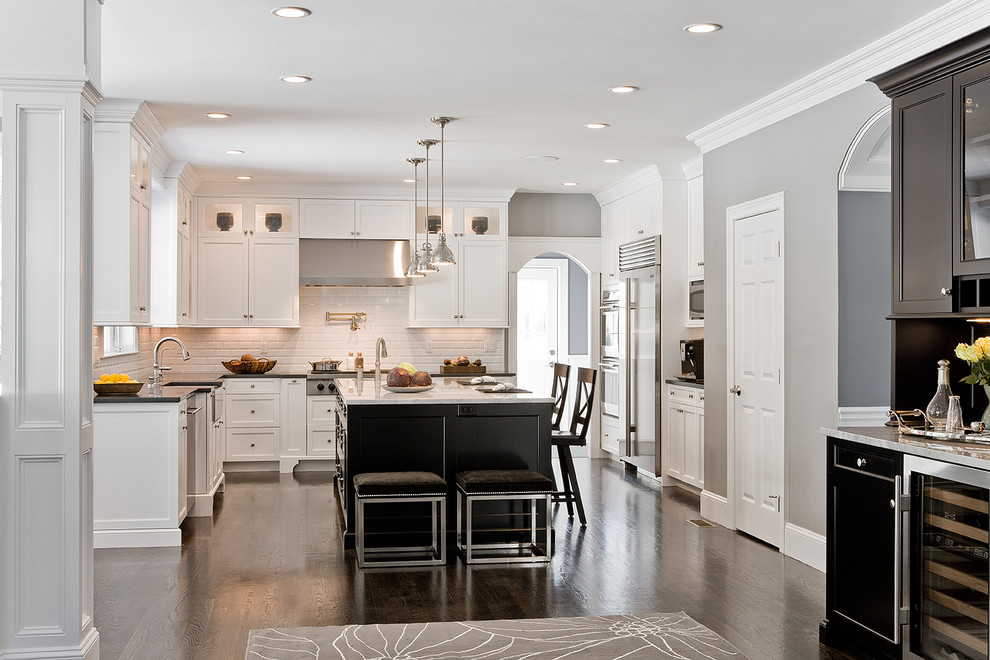 Design ideas for a traditional l-shaped kitchen in Boston with stainless steel appliances, a farmhouse sink, white cabinets, white splashback and subway tile splashback.