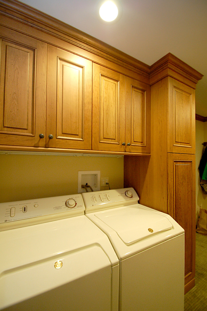Mid-sized traditional u-shaped laundry room in Newark with an undermount sink, raised-panel cabinets, medium wood cabinets, granite benchtops, beige splashback, subway tile splashback and carpet.