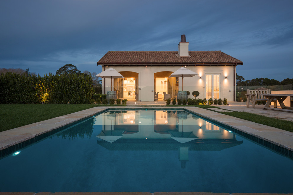 Mid-sized country backyard rectangular pool in Auckland with natural stone pavers.