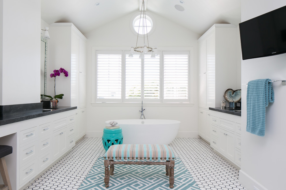 This is an example of a large beach style master bathroom in Orange County with shaker cabinets, white cabinets, a freestanding tub, white walls and ceramic floors.
