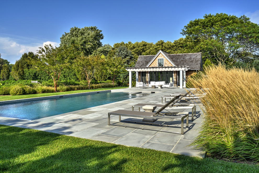 This is an example of a beach style backyard rectangular lap pool in New York with a pool house.