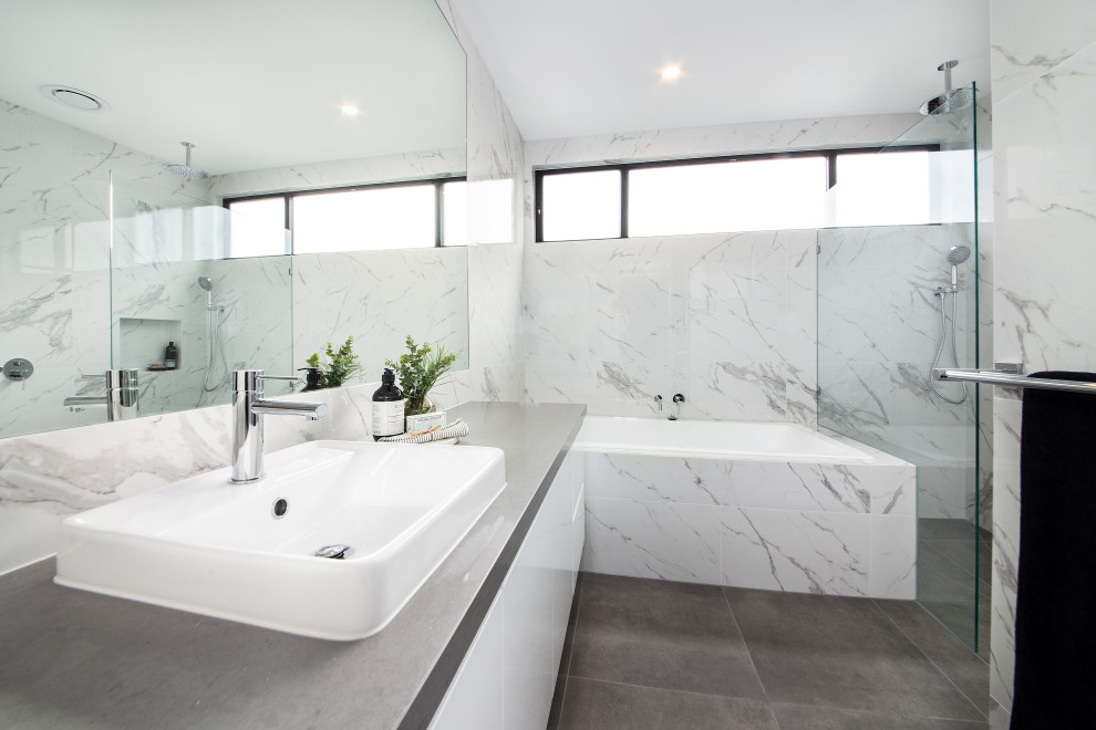 Contemporary bathroom in Melbourne with flat-panel cabinets, white cabinets, an undermount tub, an alcove shower, white tile, a drop-in sink, grey floor, a hinged shower door, grey benchtops, a single vanity and a floating vanity.