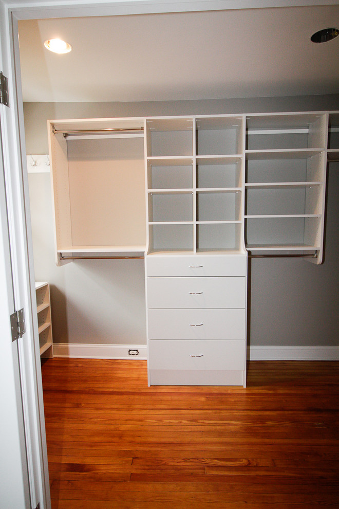 Mid-sized transitional gender-neutral walk-in wardrobe in New York with flat-panel cabinets, white cabinets and medium hardwood floors.
