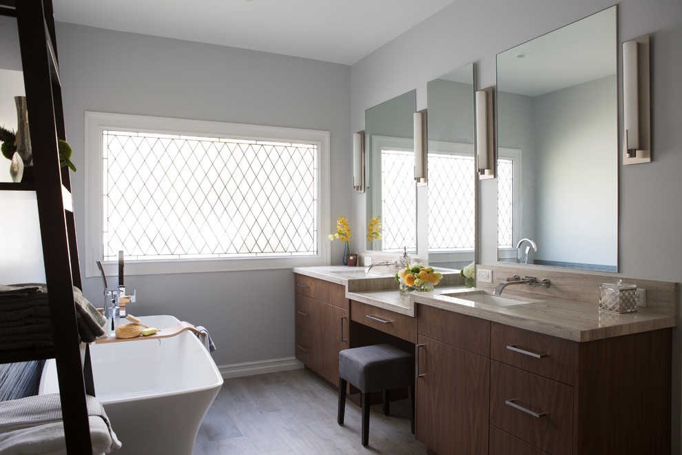 Photo of a large contemporary master bathroom in Los Angeles with flat-panel cabinets, medium wood cabinets, a freestanding tub, a corner shower, blue tile, glass tile, grey walls, porcelain floors, an undermount sink and limestone benchtops.