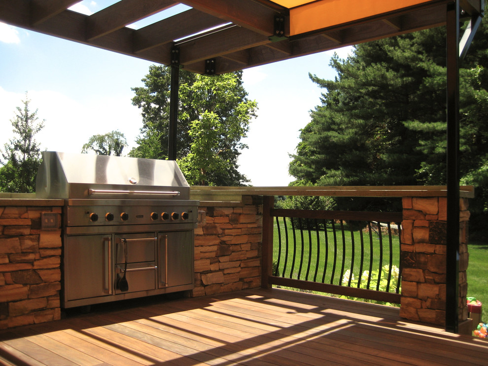 This is an example of a mid-sized contemporary backyard deck in Philadelphia with an outdoor kitchen and an awning.