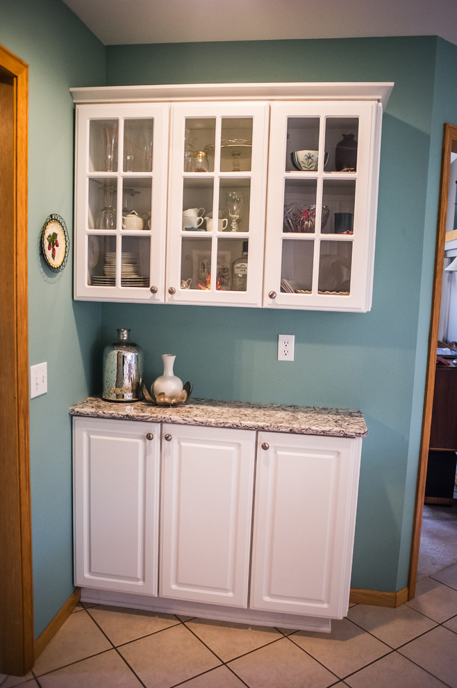 Inspiration for a small transitional u-shaped ceramic tile eat-in kitchen remodel with a drop-in sink, raised-panel cabinets, white cabinets, granite countertops, brown backsplash, porcelain backsplash, white appliances and an island
