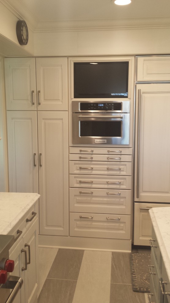Eat-in kitchen - small transitional u-shaped ceramic tile eat-in kitchen idea with a double-bowl sink, raised-panel cabinets, white cabinets, marble countertops, white backsplash, subway tile backsplash, stainless steel appliances and an island