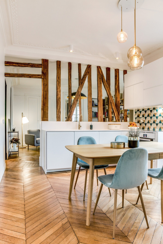 Photo of a mid-sized scandinavian single-wall open plan kitchen in Paris with flat-panel cabinets, white cabinets, multi-coloured splashback, brown floor, white benchtop, an undermount sink, terra-cotta splashback, panelled appliances, light hardwood floors and no island.