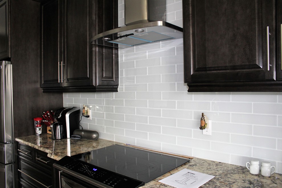 Example of a mid-sized transitional galley eat-in kitchen design in Tampa with raised-panel cabinets, dark wood cabinets, granite countertops, multicolored backsplash, glass tile backsplash, stainless steel appliances and no island