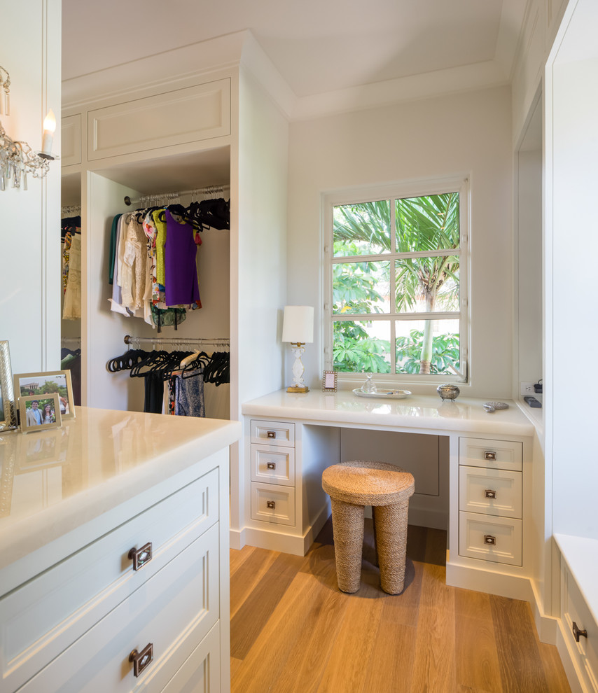 Design ideas for a small women's built-in wardrobe in Miami with flat-panel cabinets, white cabinets and plywood floors.