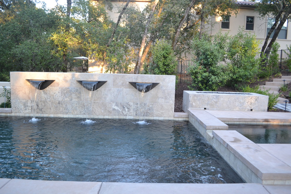 Photo of a mid-sized contemporary backyard custom-shaped pool in Sacramento with a water feature and stamped concrete.