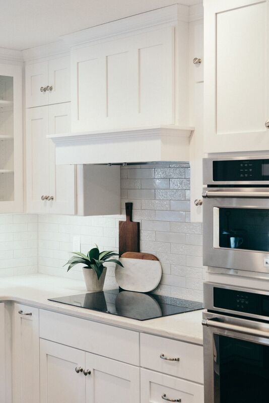Example of a mid-sized u-shaped dark wood floor and brown floor open concept kitchen design with a farmhouse sink, recessed-panel cabinets, white backsplash, glass tile backsplash, stainless steel appliances and an island