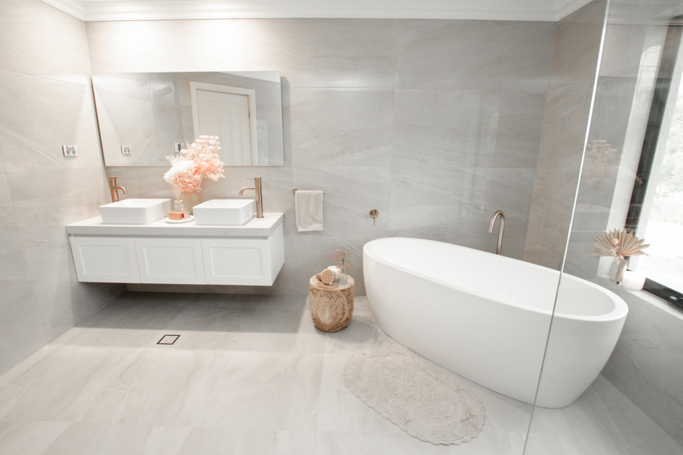 This is an example of a large contemporary master bathroom in Sydney with shaker cabinets, white cabinets, a freestanding tub, an open shower, a one-piece toilet, gray tile, grey walls, a vessel sink, grey floor, an open shower, a niche, a double vanity and a floating vanity.